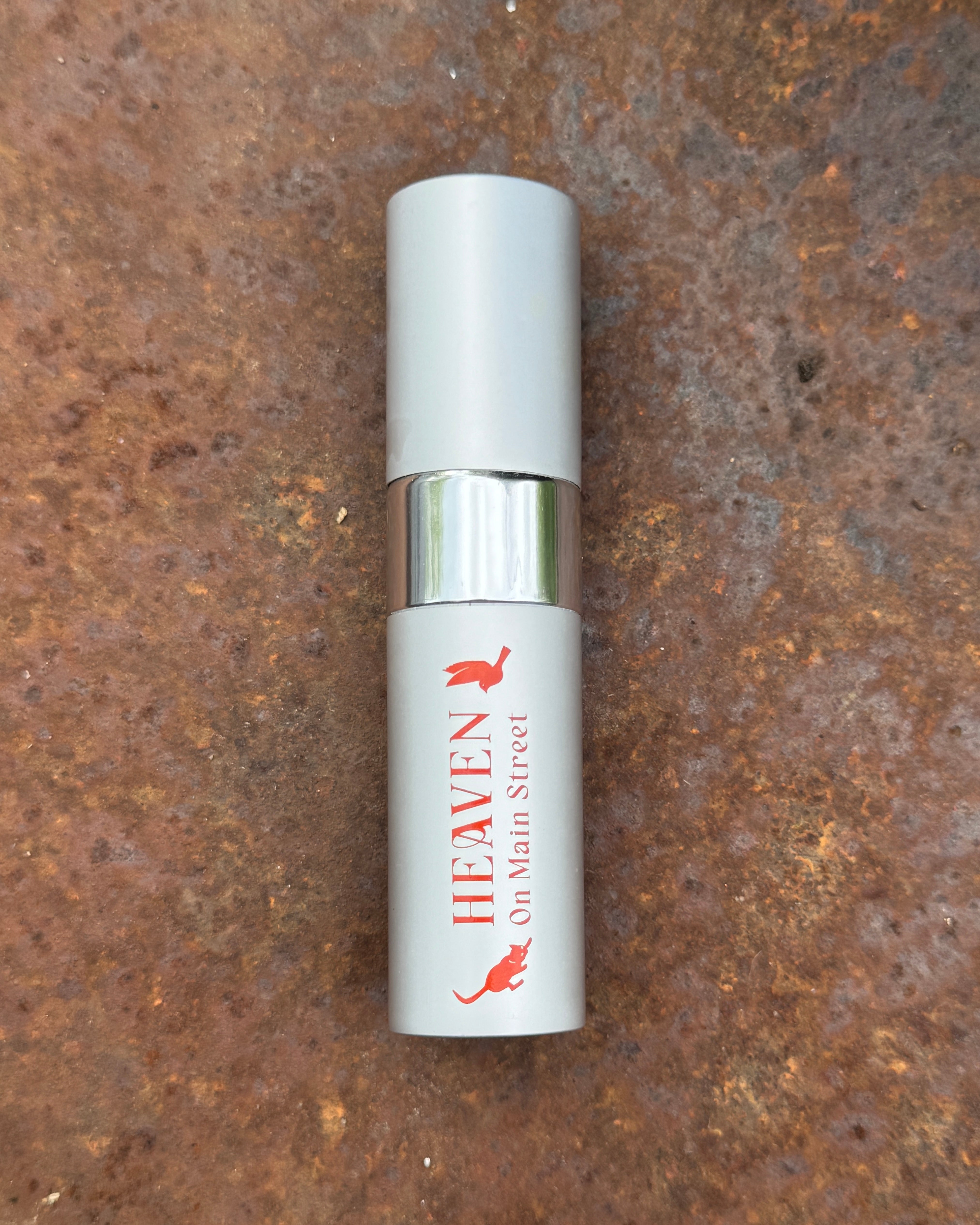 Small cylindrical container with 'Heaven on Main Street' branding on a rusty metal surface